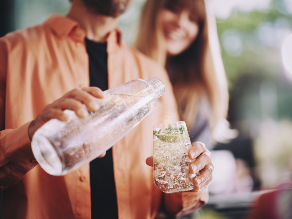 Mężczyzna nalewa gazowaną wodę z butelki SodaStream do szklanki